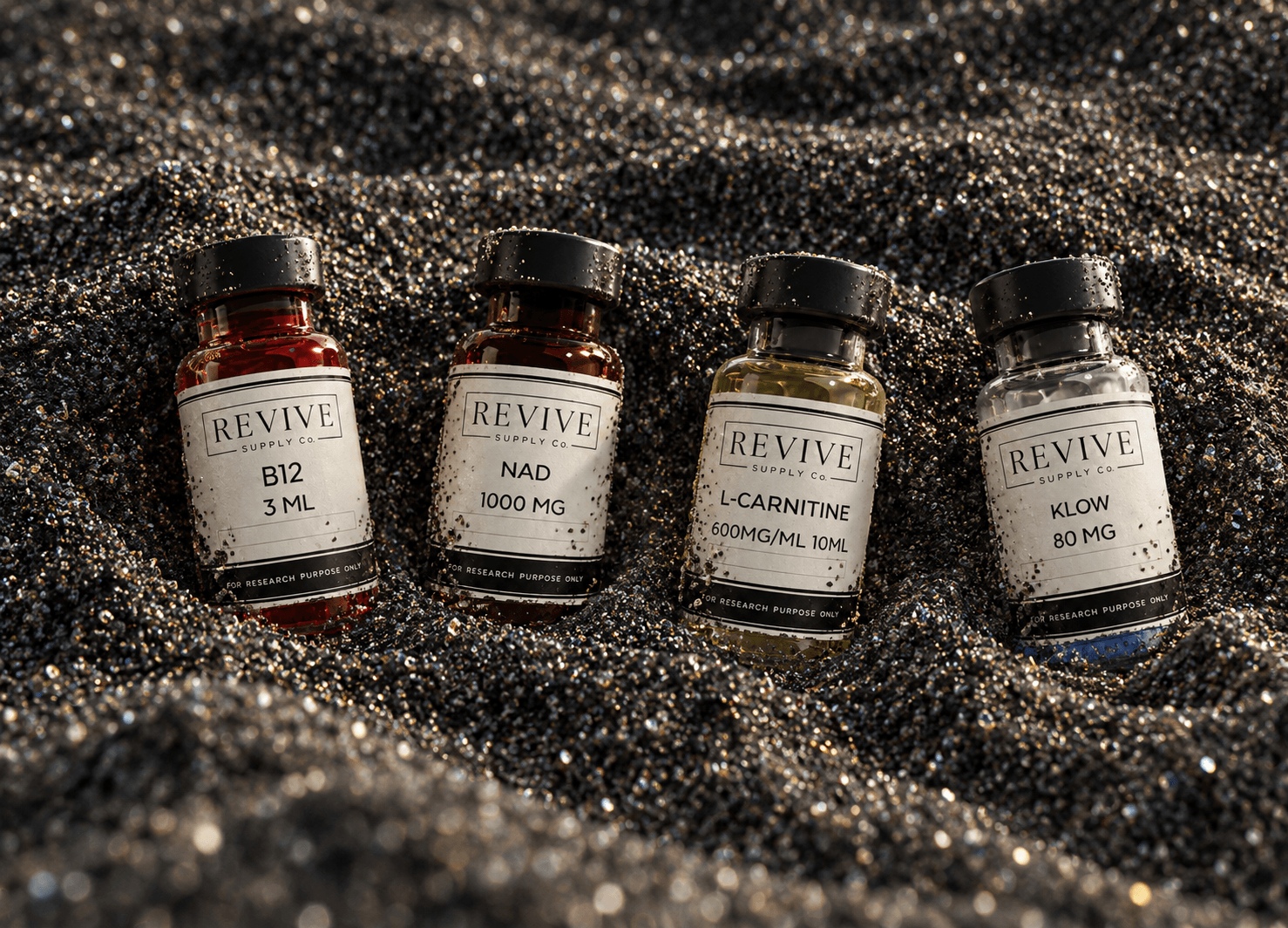 Revive Supply Co. B12, NAD, L-Carnitine, and KLOW vials resting on dark sand